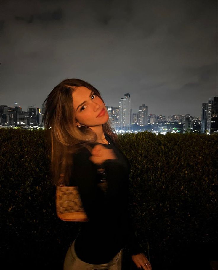 a woman standing in front of a city at night