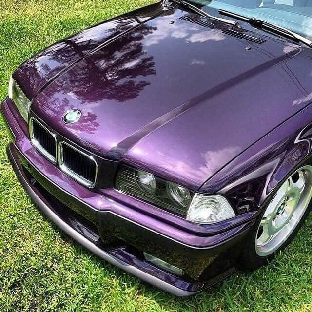 a purple car parked on top of a lush green field