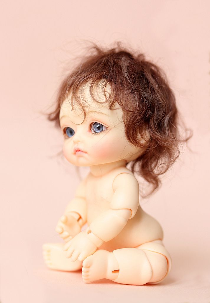 a small doll sitting on the ground next to a teddy bear and pink wall background