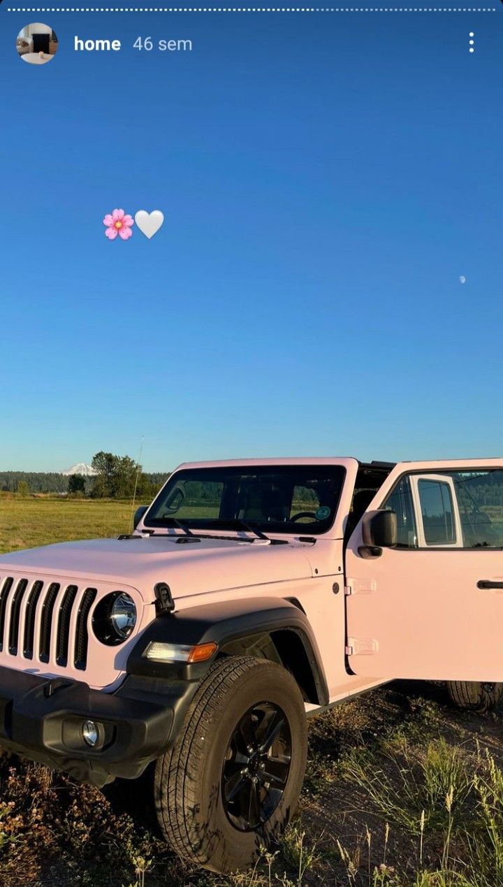 a pink jeep parked in a field with a heart shaped balloon flying over the top