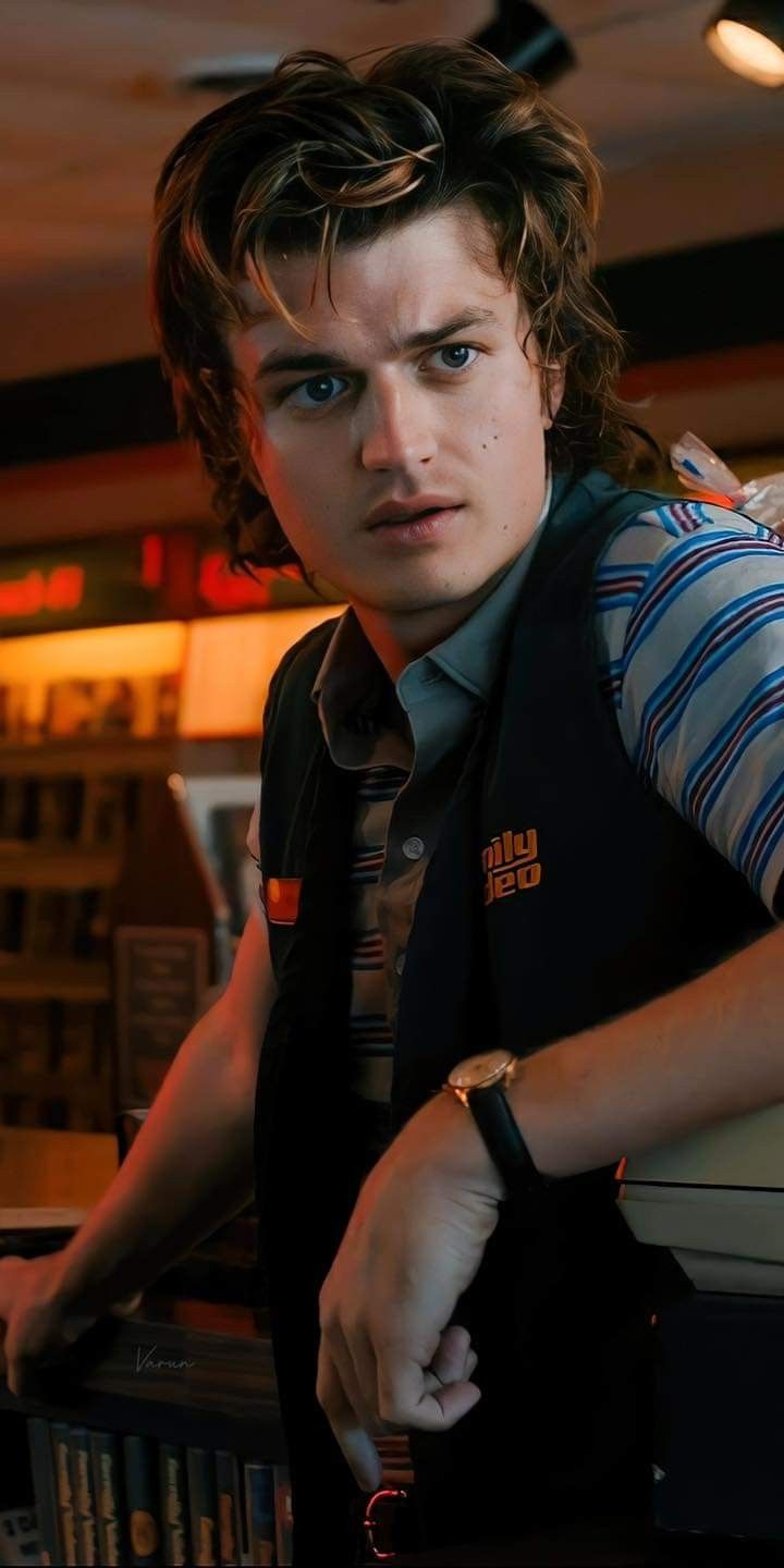 a young man leaning on a counter in a restaurant looking at the camera with an intense look