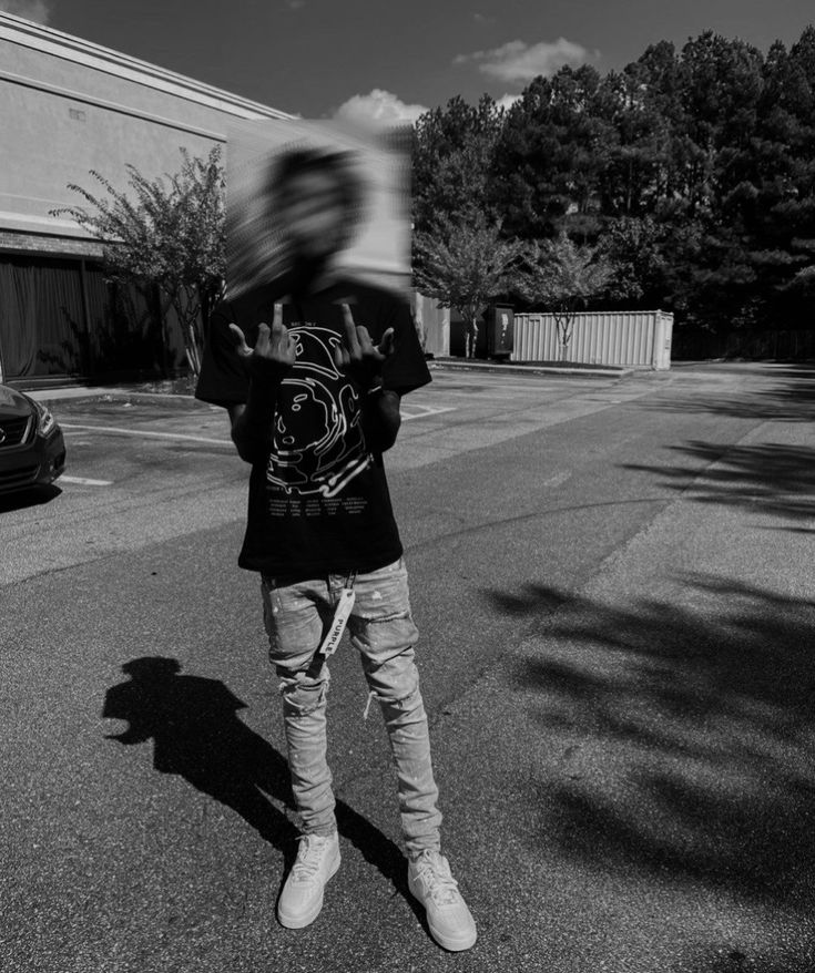 a man standing on the side of a road holding a skateboard in his hands