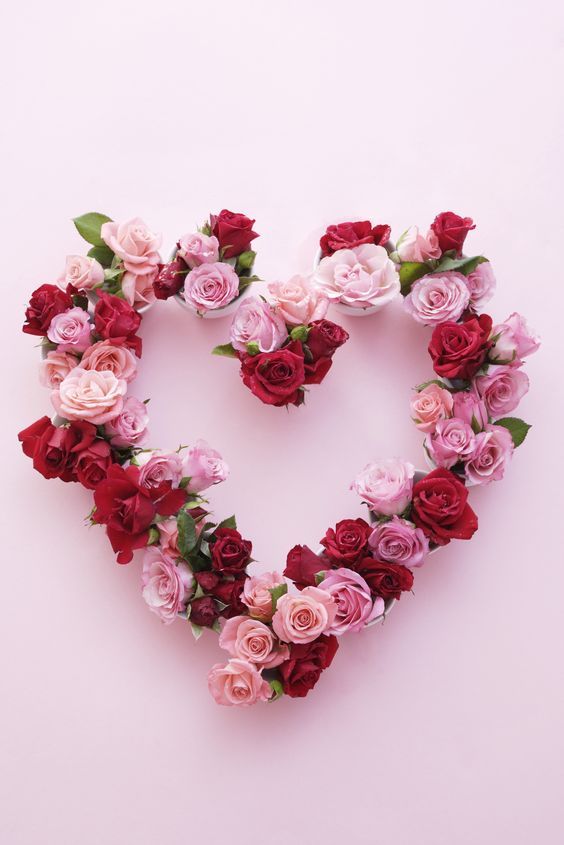 a heart made out of flowers on a pink background with the word love spelled in it