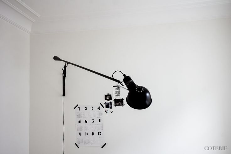 a black lamp hanging from the side of a white wall next to a light bulb