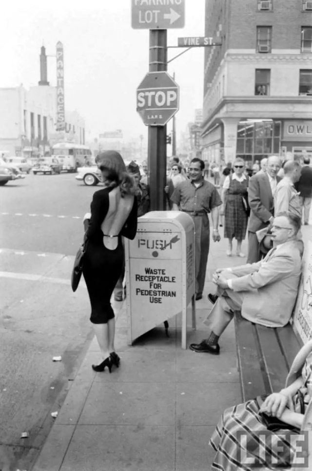 an old black and white photo of people sitting on a bench in front of a stop sign