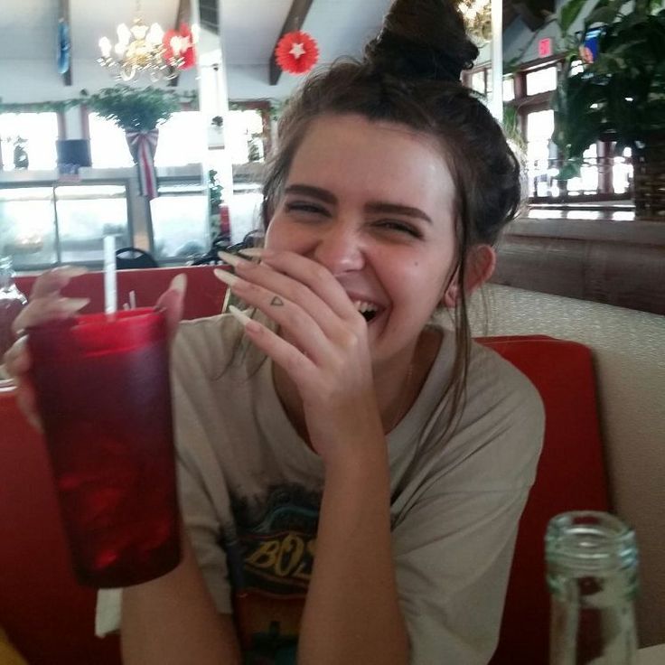 a woman sitting at a table with a drink in her hand