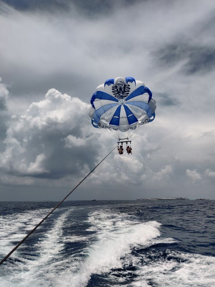 a parasail being lifted from the back of a boat in the ocean on a cloudy day