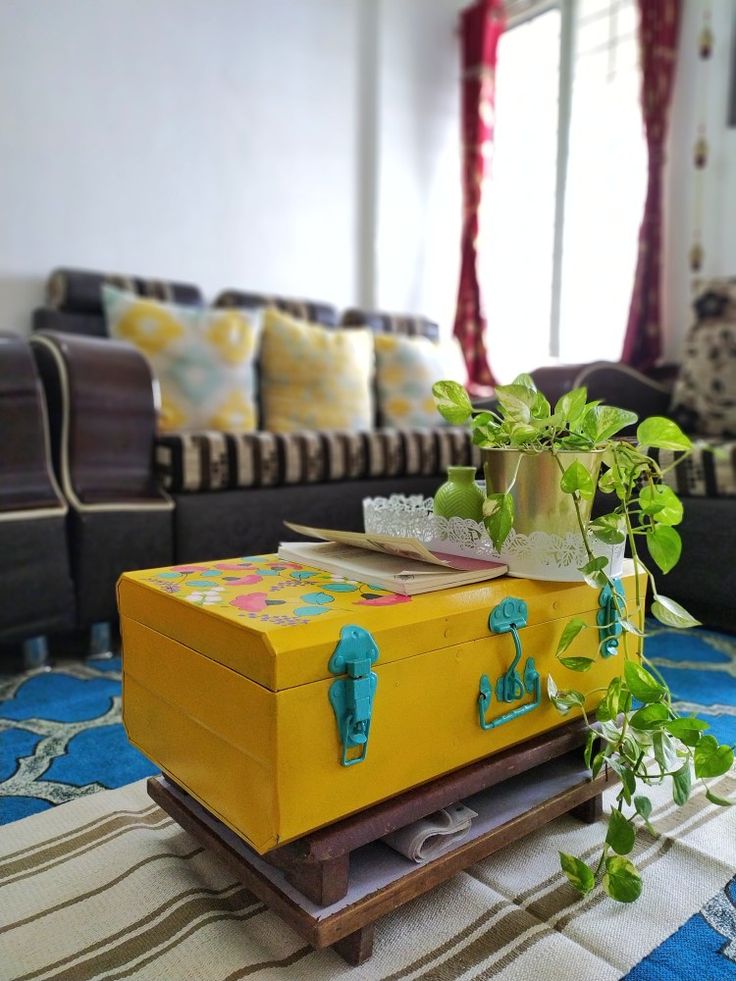 a yellow suitcase sitting on top of a blue and white rug next to a couch