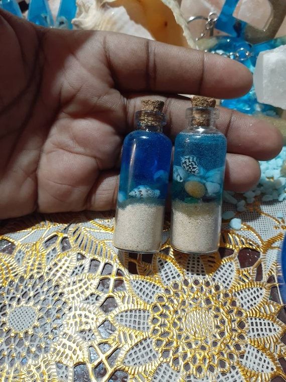 two small bottles with sand inside sitting on a doily