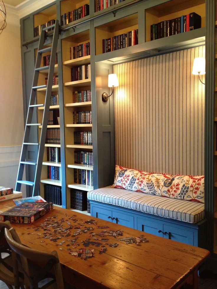 a room with bookshelves and a ladder in the wall next to a couch