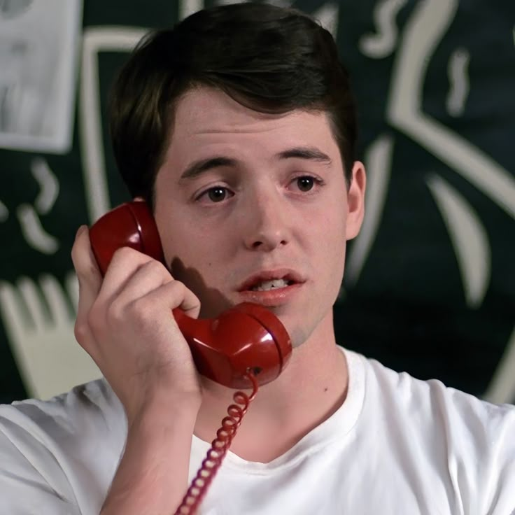 a young man talking on a red telephone