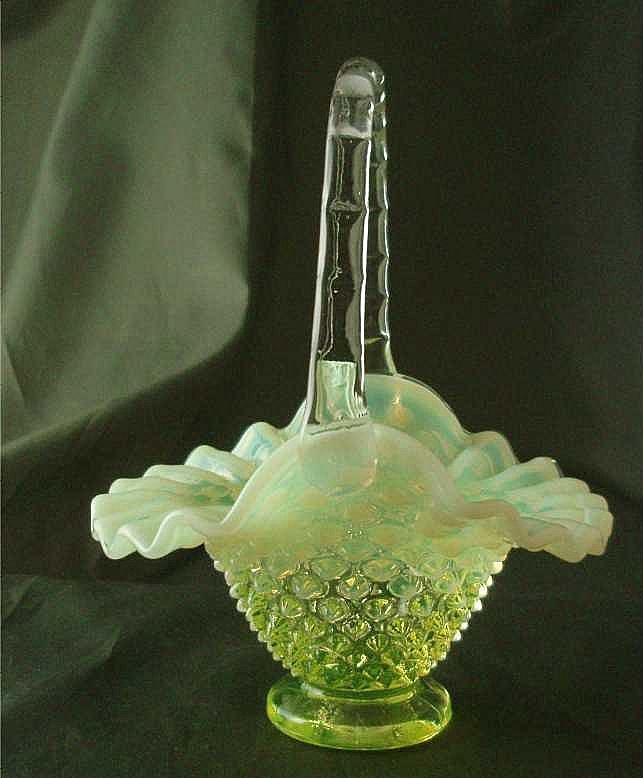 a green glass vase sitting on top of a black table