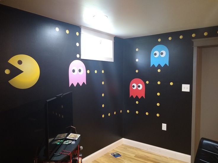 a room with black walls decorated with pacman wall decals and lights on the ceiling