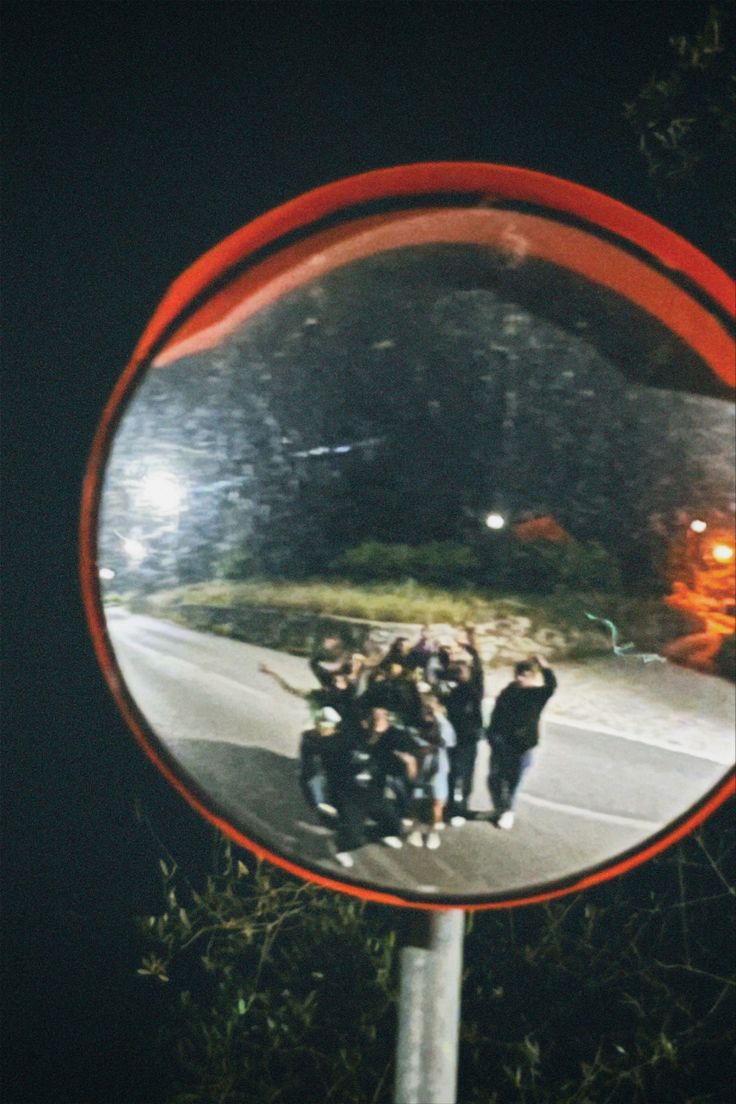 a group of people standing in front of a mirror on the side of a road