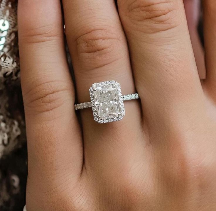 a woman's hand with a diamond ring on top of her finger and an engagement band