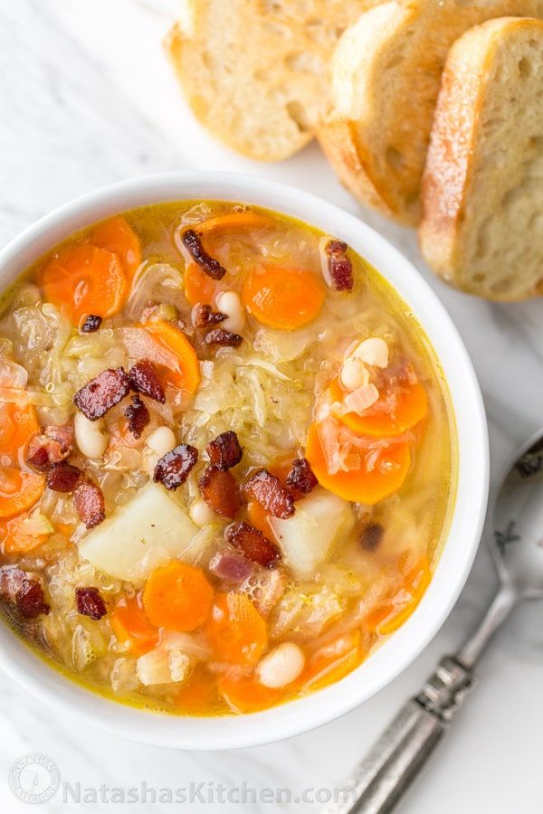 a bowl of soup with carrots, beans and bread