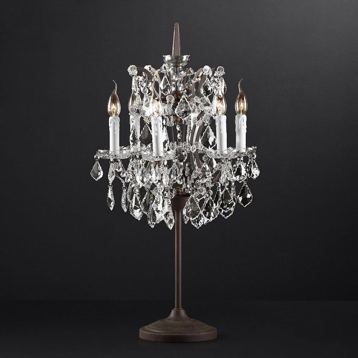 a crystal chandelier on a metal stand with four candles in the center and one candle