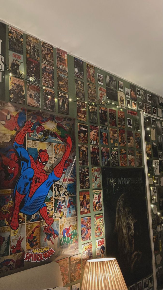 a wall covered in comic books and pictures with a lamp on the table next to it