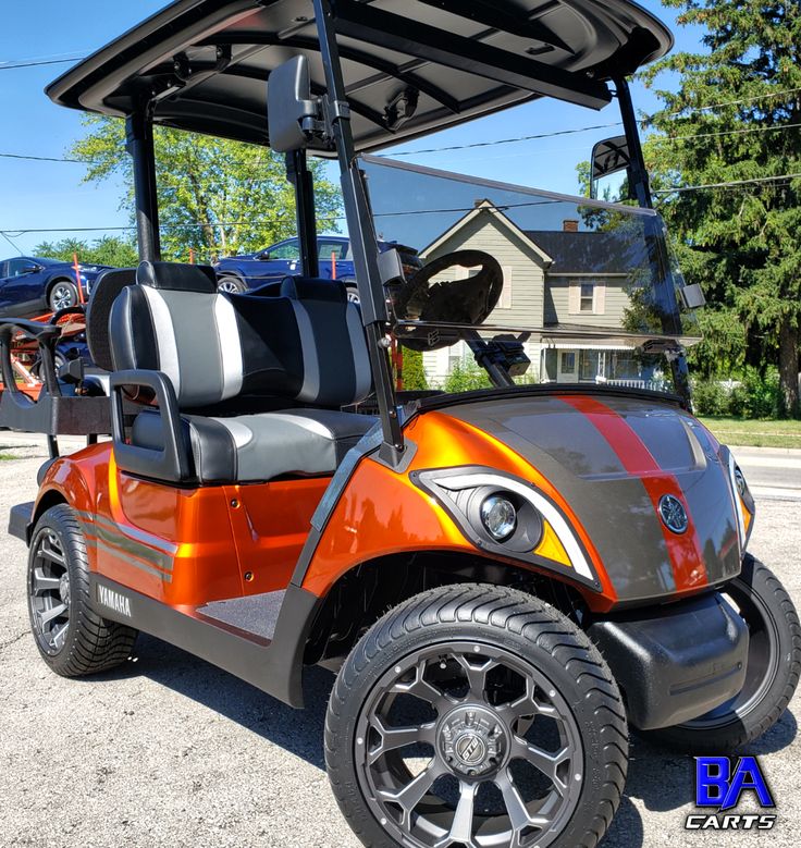 an orange and black golf cart parked on the street