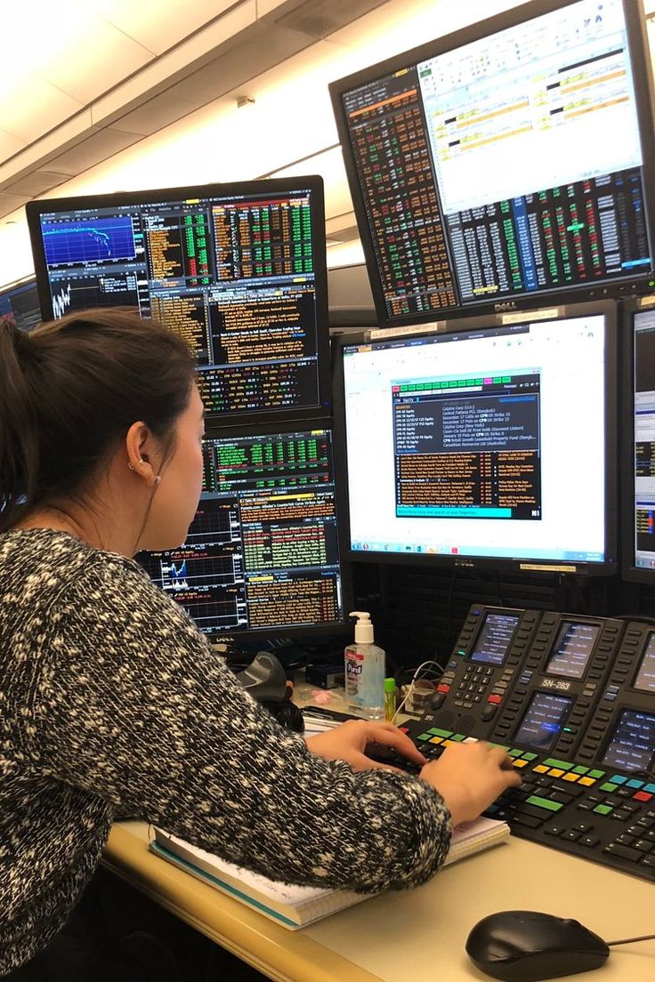 a woman sitting at a desk in front of multiple computer monitors with screens on the wall