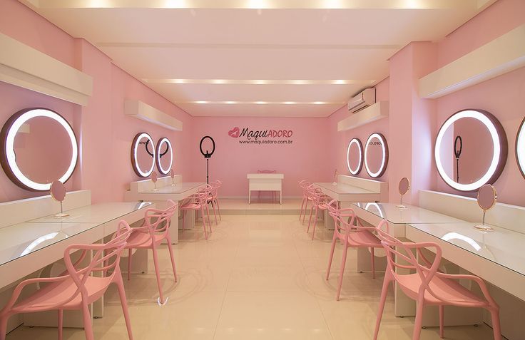 a pink and white room with round mirrors on the wall, chairs and tables in front of them