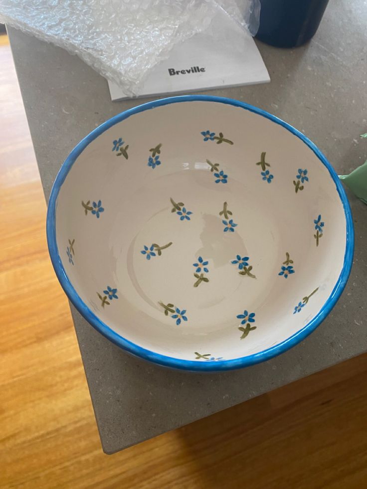 a blue and white bowl sitting on top of a counter next to a green cup