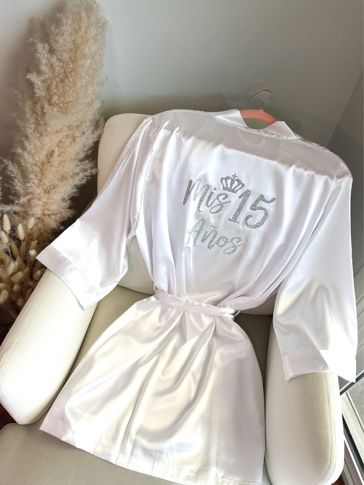 "Get ready for your Mis Quince Años celebration in style with our Quinceañera Satin Robes!  Crafted from soft and silky high-quality satin, these robes are designed to make you feel like a princess on your special day. With different options for text color and designs on the back side, you can customize your robe to match your unique style and personality. Not only are these robes perfect for getting ready, but they're also ideal for Instagram and Pinterest photos. Order yours Mis Quince robe to Personalized Quince Robe, Champagne Quince Robe, White Quince Decorations, 15 Ideas Quinceanera Decorations, Quince Robe Ideas, Mis Quince Robe, 15th Quinceanera Quince Ideas, Destination Quinceanera, Quinceañera Robes