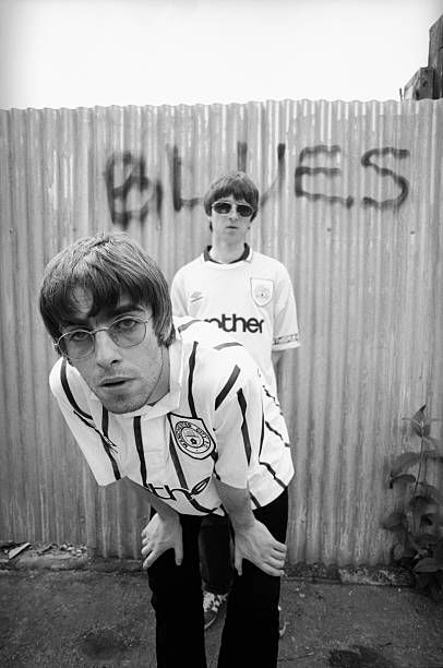 two young men standing next to each other in front of a wall with graffiti on it