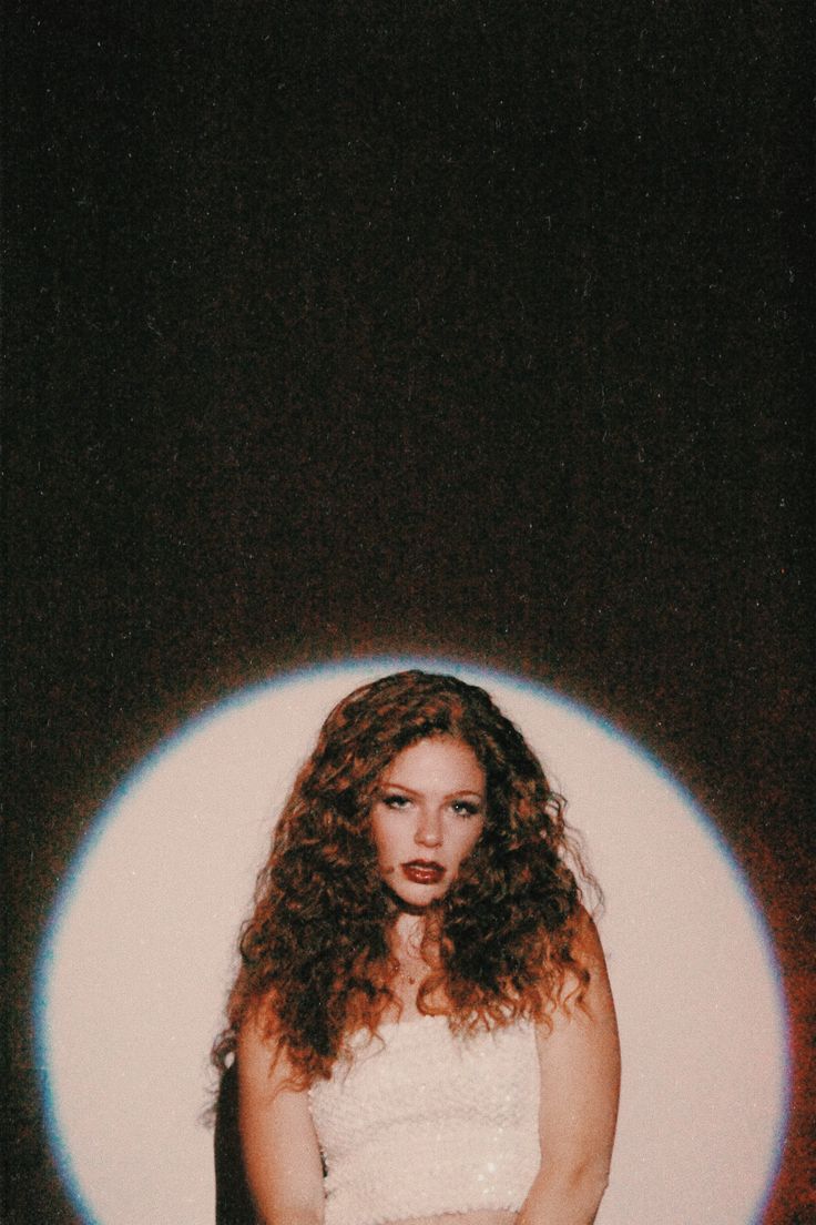 a woman with curly hair standing in front of a light