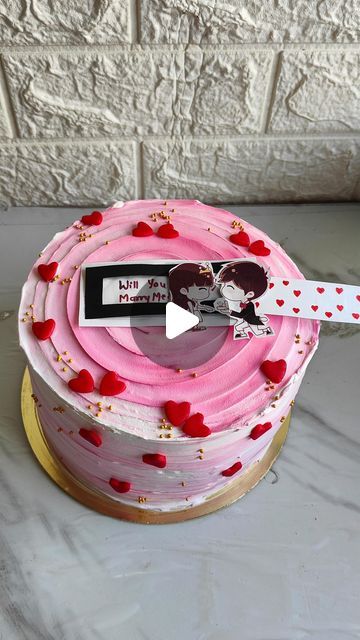 a cake with pink frosting and red hearts on it, decorated with a knife