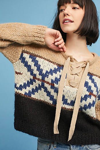 a woman wearing a sweater and jeans poses for the camera with her hands on her hips