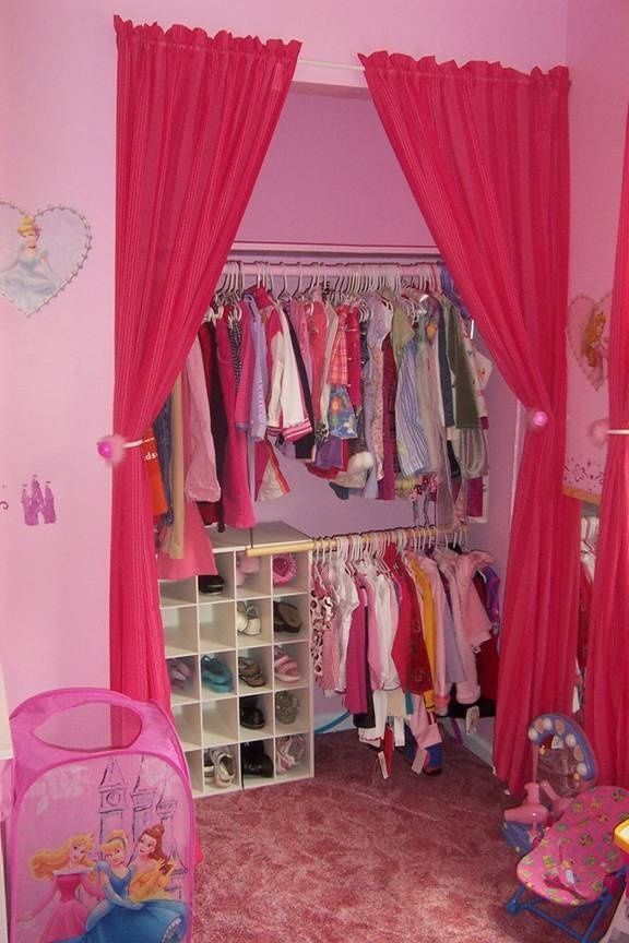 a bedroom with pink walls and lots of clothes hanging on the closet doors, in front of a princess bed