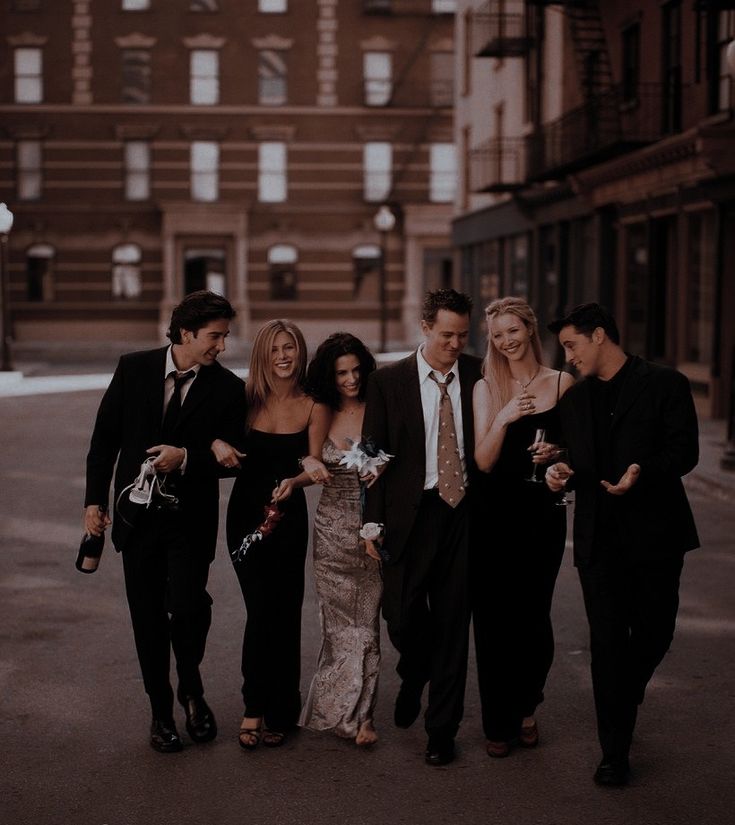 a group of people standing next to each other in front of a tall brick building