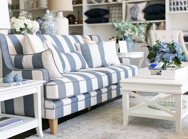 a blue and white striped couch in a room filled with shelves full of vases