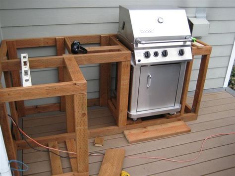 an outdoor kitchen built into the side of a house that is being constructed with wood