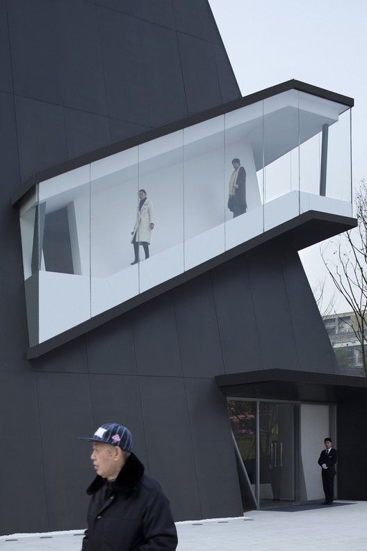 a man is walking in front of a building that has glass windows on the side