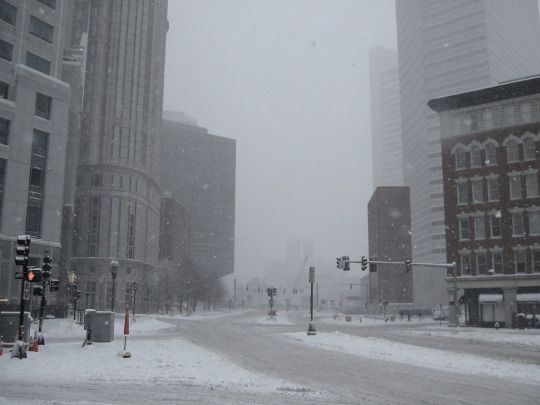 a snowy street with traffic lights and buildings in the background