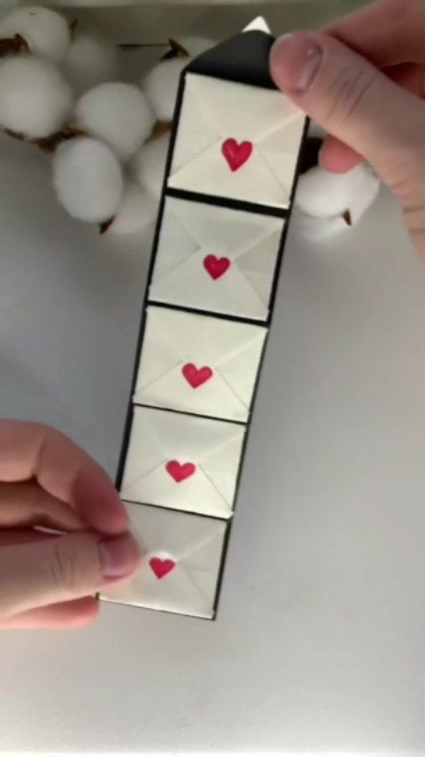 someone is placing hearts on an origami tower