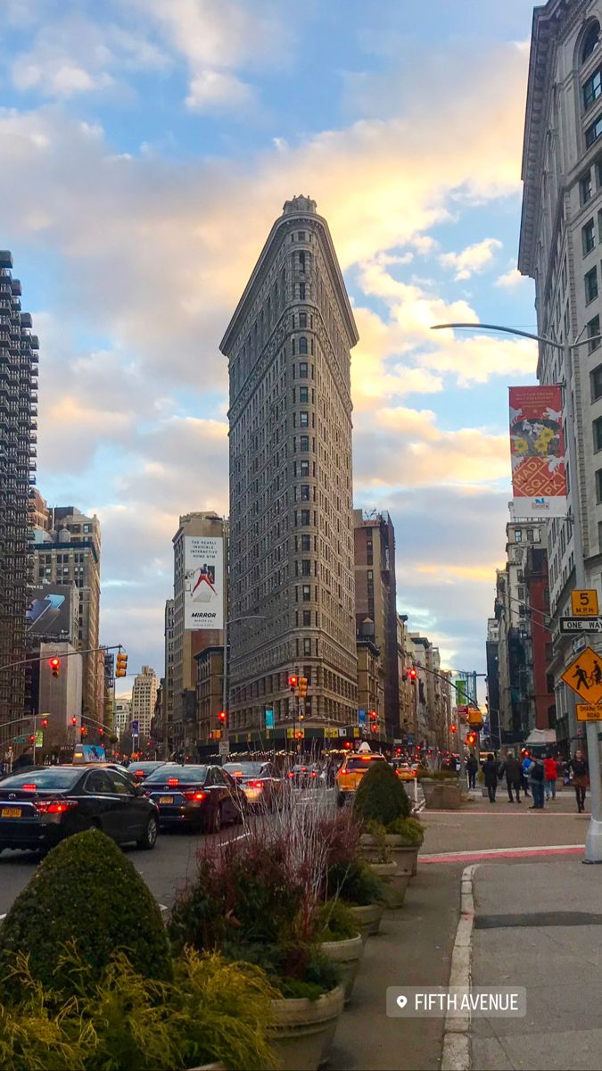 a city street filled with lots of traffic and tall buildings in the background, at sunset