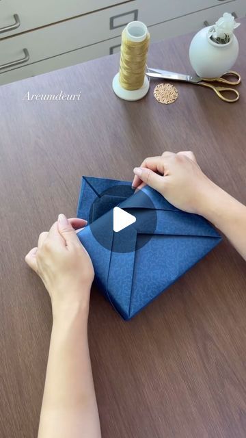 someone is making an origami envelope out of blue paper