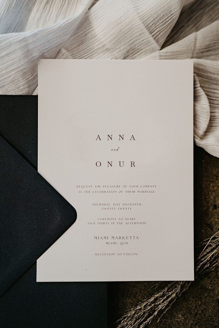 the wedding stationery is laid out on top of black and white paper, which reads anna onur