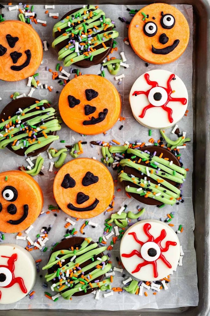 halloween decorated cookies on a baking sheet with sprinkles and eyes painted on them