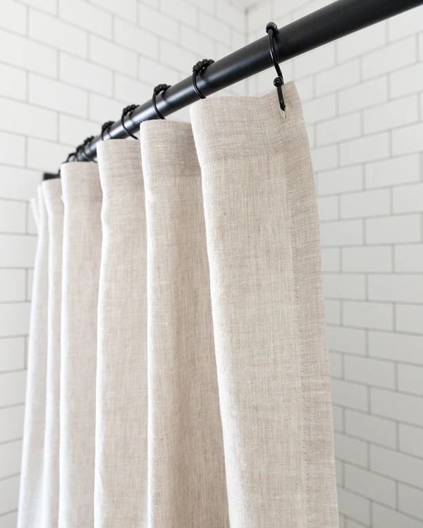 white curtains hanging on a black rod in front of a brick wall