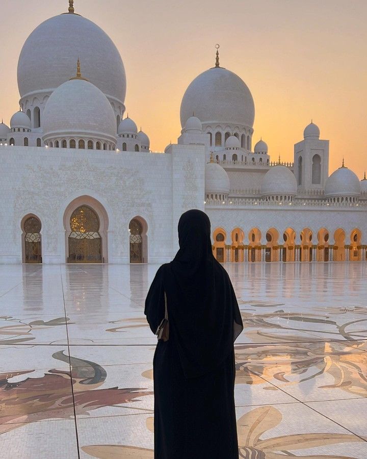 a person standing in front of a white building with many arches and domes on it