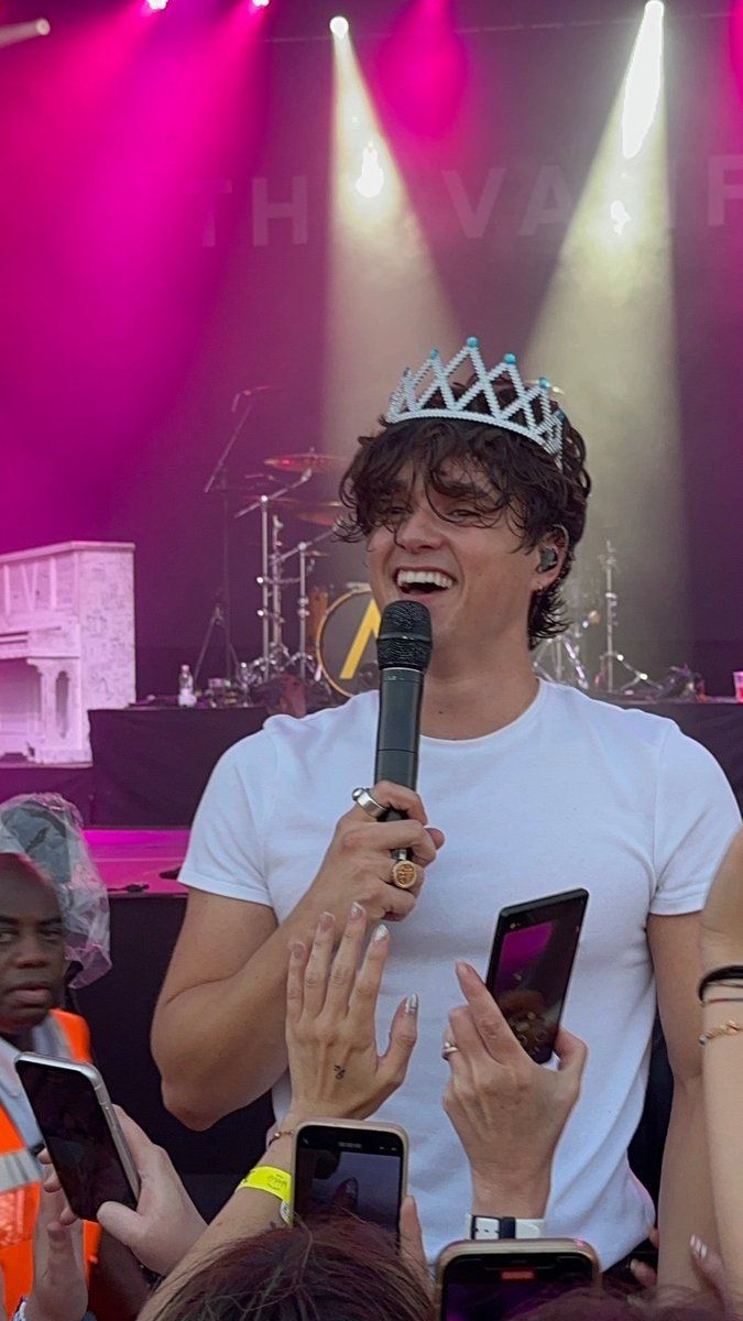 a man holding a microphone while wearing a crown