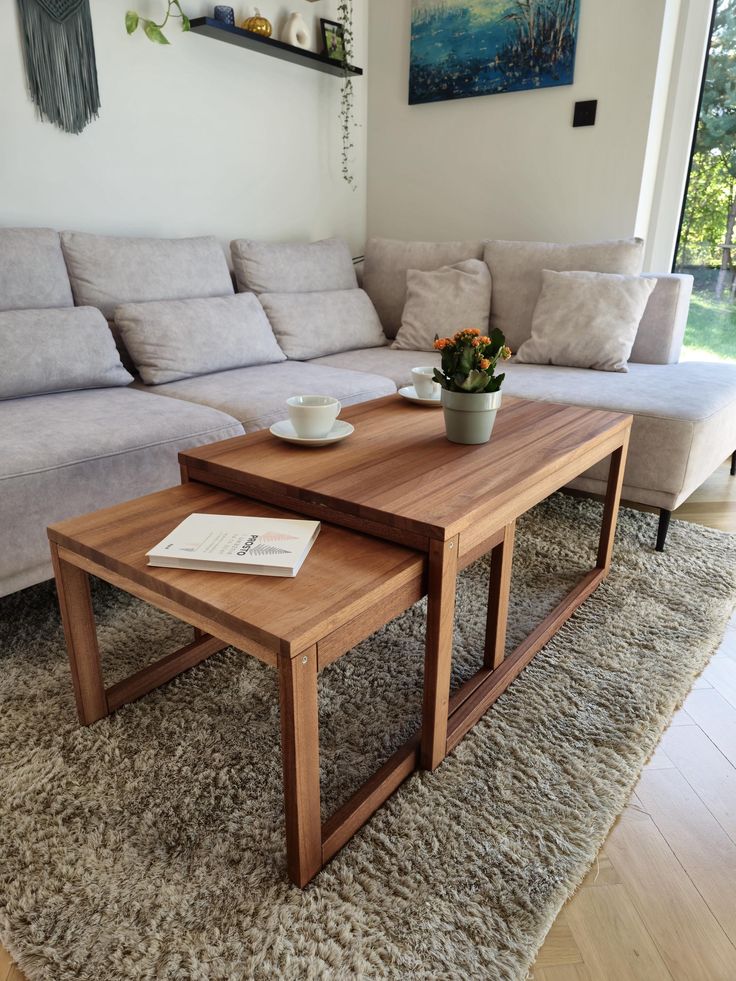 two wooden tables sitting on top of a carpeted floor next to a gray couch