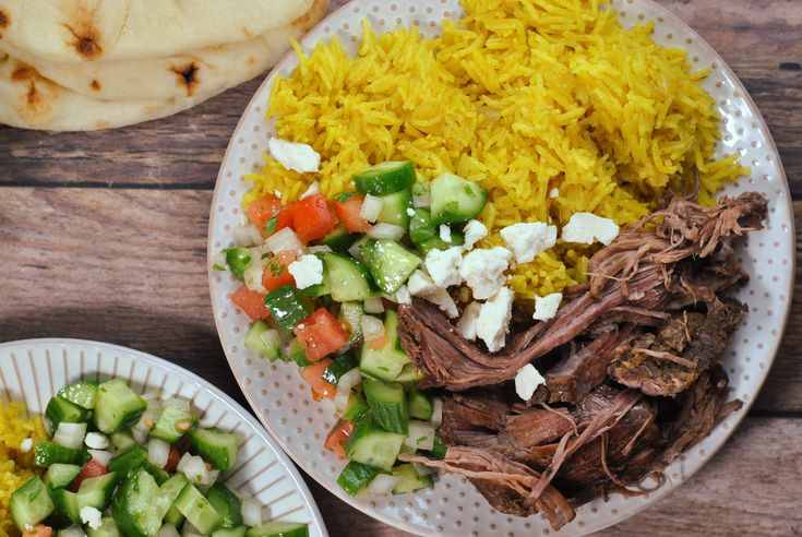 the meal is prepared and ready to be eaten on the table, including rice, meat, cucumbers, and other vegetables