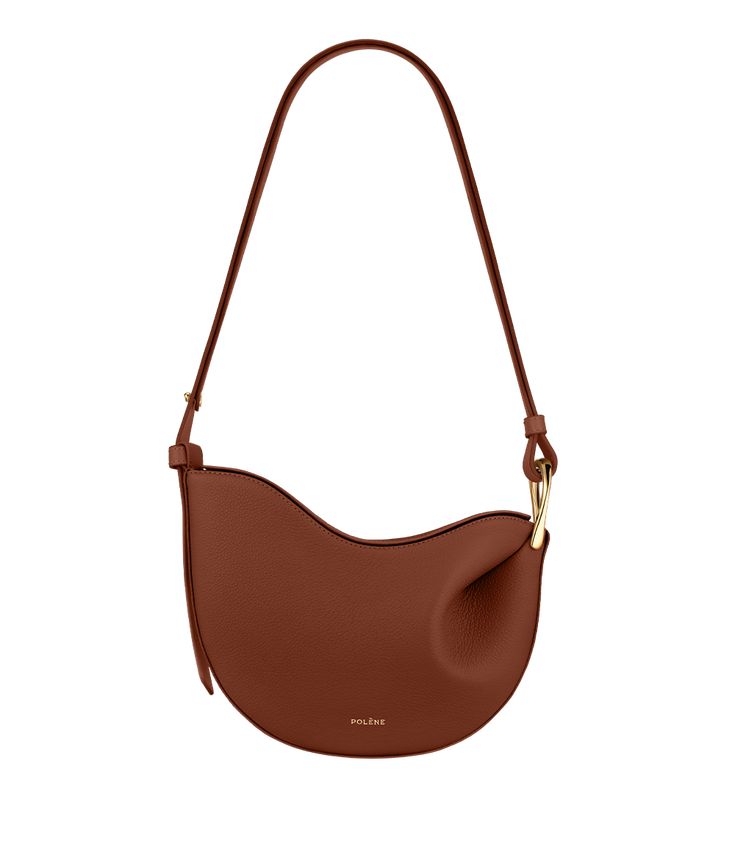 Obtained by modeling the leather on a wooden mould, the “Tonca” bag’s roundness is shaped by its folds that blend into a twisted metal buckle. The bag’s contrasting body and shoulder strap feature smooth and textured leathers. Polene Cyme Cognac, Polene Cyme Mini Cognac, Polene Numero Neuf Micro, Polene Paris Bag Tonca, Cognac Bag, Micro Bags, Twisted Metal, Upcycled Leather, Best Wallet