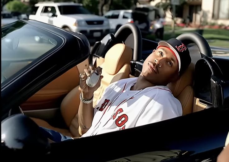 a man sitting in the driver's seat of a sports car with his hand up