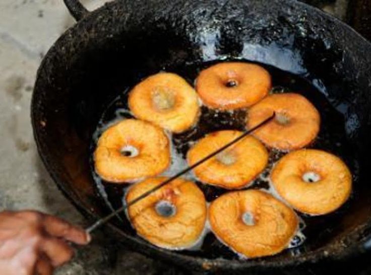 there are many donuts being cooked in a pot on the stove with tongs